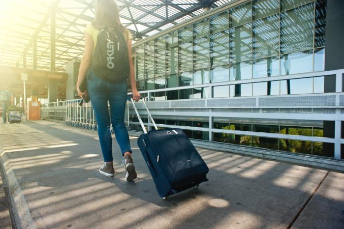 Woman Walking Through Airport With Suitcase - 5 Practical Ways to Ease Your Travel Anxiety This Summer